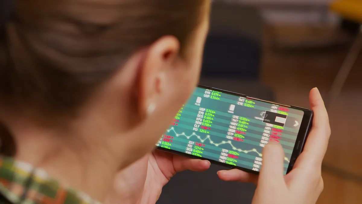 Kvinde følger aktiekurser og grafer på sin smartphone